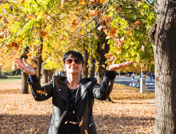 Woman with sunglasses standing on autumn leaves