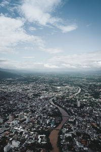 Aerial view of cityscape against sky with riber running though