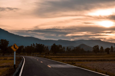 Road passing through mountains during sunset