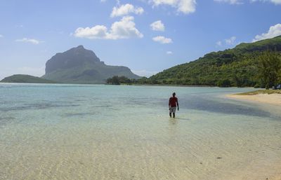 Rear view of people on beach against sky