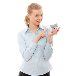 Young woman using phone while standing against white background