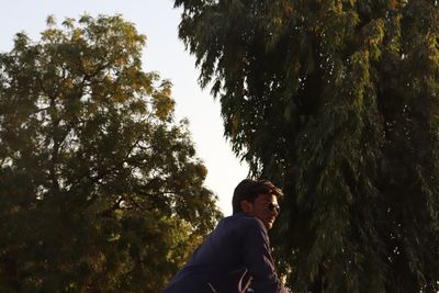 Low angle view of man standing against trees
