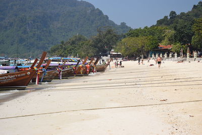 People on riverbank against clear sky