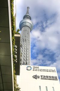 Low angle view of communications tower against cloudy sky