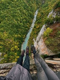 Two pairs of tourist feet high above the river in the mountains