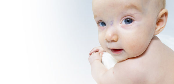 Close-up of cute baby boy against white background