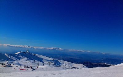 Scenic view of snowcapped mountains against blue sky