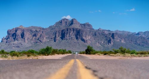 Road by rocky mountains against clear sky