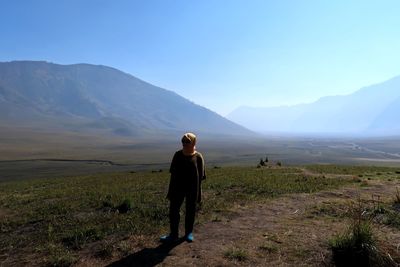 Woman standing on land against clear blue sky