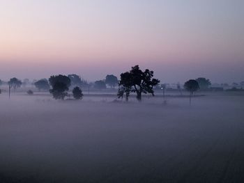 Scenic view of fog on landscape in morning against clear sky