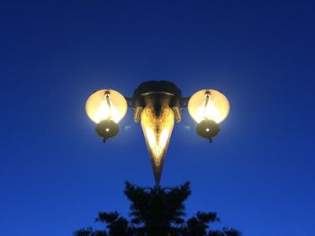 Low angle view of illuminated street light against clear blue sky