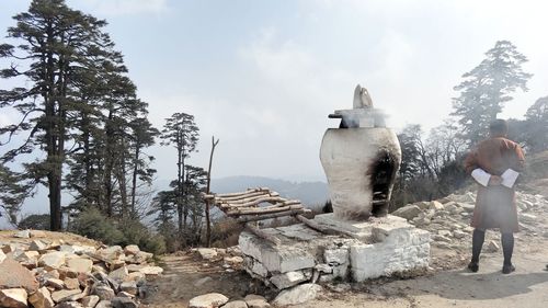 Full length rear view of man standing by old oven against sky