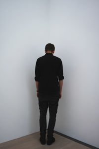 Rear view of man standing against wall