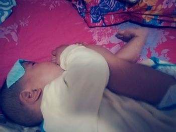 Close-up of baby relaxing on bed at home