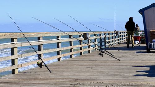 Fishing rods  on pier against sky