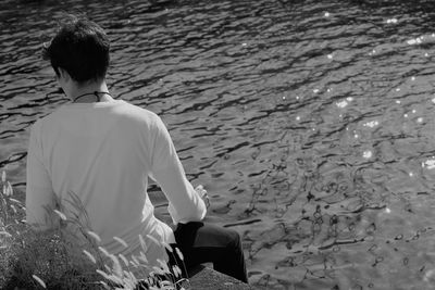 Rear view of man sitting by water