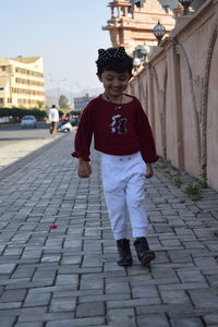 Full length portrait of boy standing on sidewalk