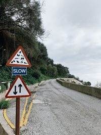 Information sign by road against sky