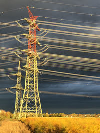 Low angle view of electricity pylon on field against sky
