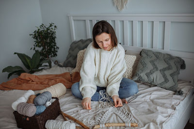 Young girl weaves using macrame technique at home