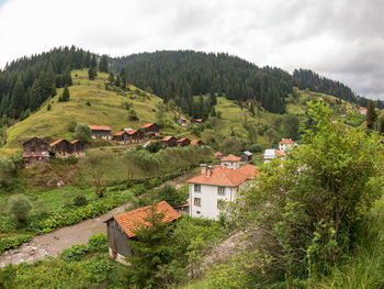 Scenic view of green landscape and houses against sky