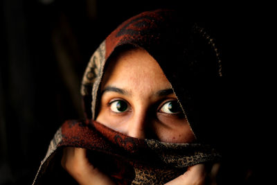 Portrait of woman wearing headscarf in dark