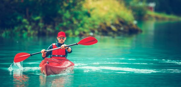 Man holding red umbrella in boat