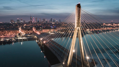 Illuminated bridge over river in city at night