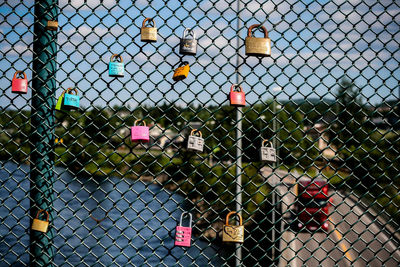 Close-up of padlocks on chainlink fence against sky