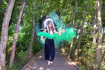 Full length of woman with arms raised in forest