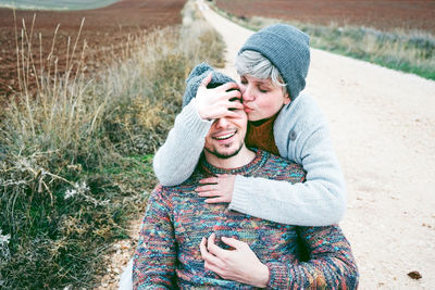 Couple embracing while sitting on road during winter