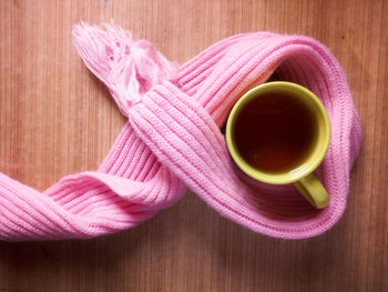 Close-up of pink scarf with tea cup on wooden table