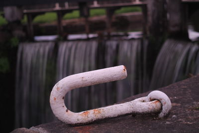 Close-up of rusty metal tied up on wood by river