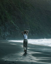 Rear view of woman standing at beach