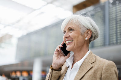 Smiling senior businesswoman on cell phone at the airport