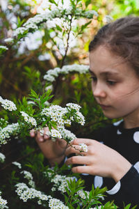 Cute girl holding flowering plant while standing outdoors