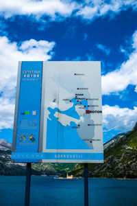 Low angle view of sign board against cloudy sky