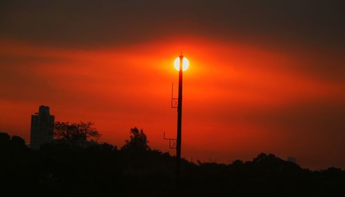 Silhouette trees against orange sky