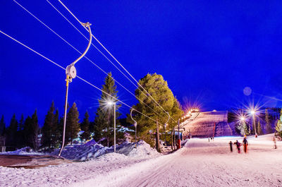 Panoramic view of illuminated street amidst field against sky at night