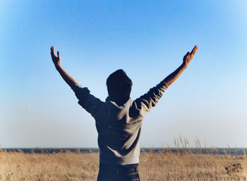 Rear view of woman standing on field against clear sky