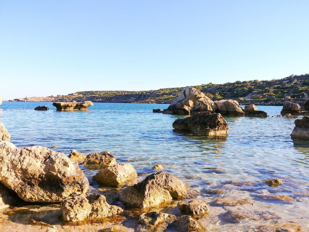 SCENIC VIEW OF ROCKS IN SEA AGAINST CLEAR BLUE SKY