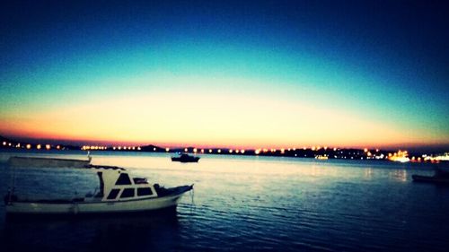 Boats in sea at sunset