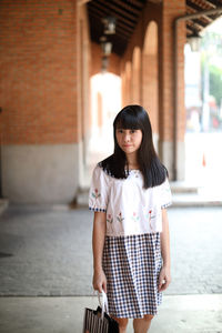 Portrait of smiling woman standing against built structure