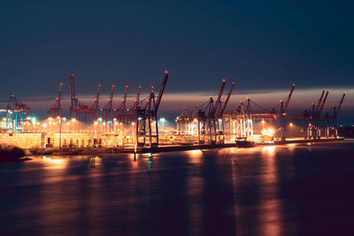 Illuminated pier at harbor against sky