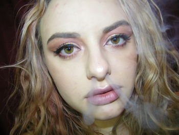 Close-up portrait of woman emitting smoke nose