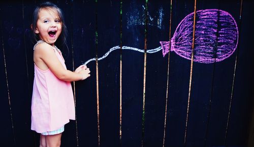 Optical illusion of happy cute girl holding balloon drawn on wooden wall