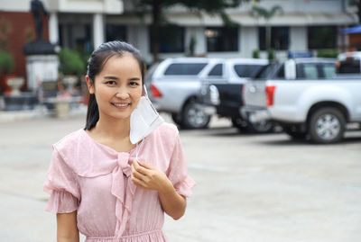 Portrait of smiling woman standing on street in city