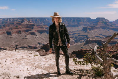 Man standing on rock against sky