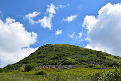 Low angle view of green mountain against sky