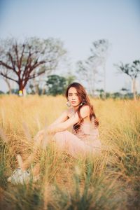 Portrait of smiling young woman sitting on land